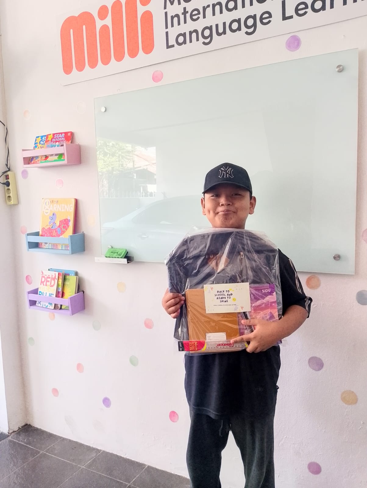 A student holding a new backpack and school supply kit provided through the project.