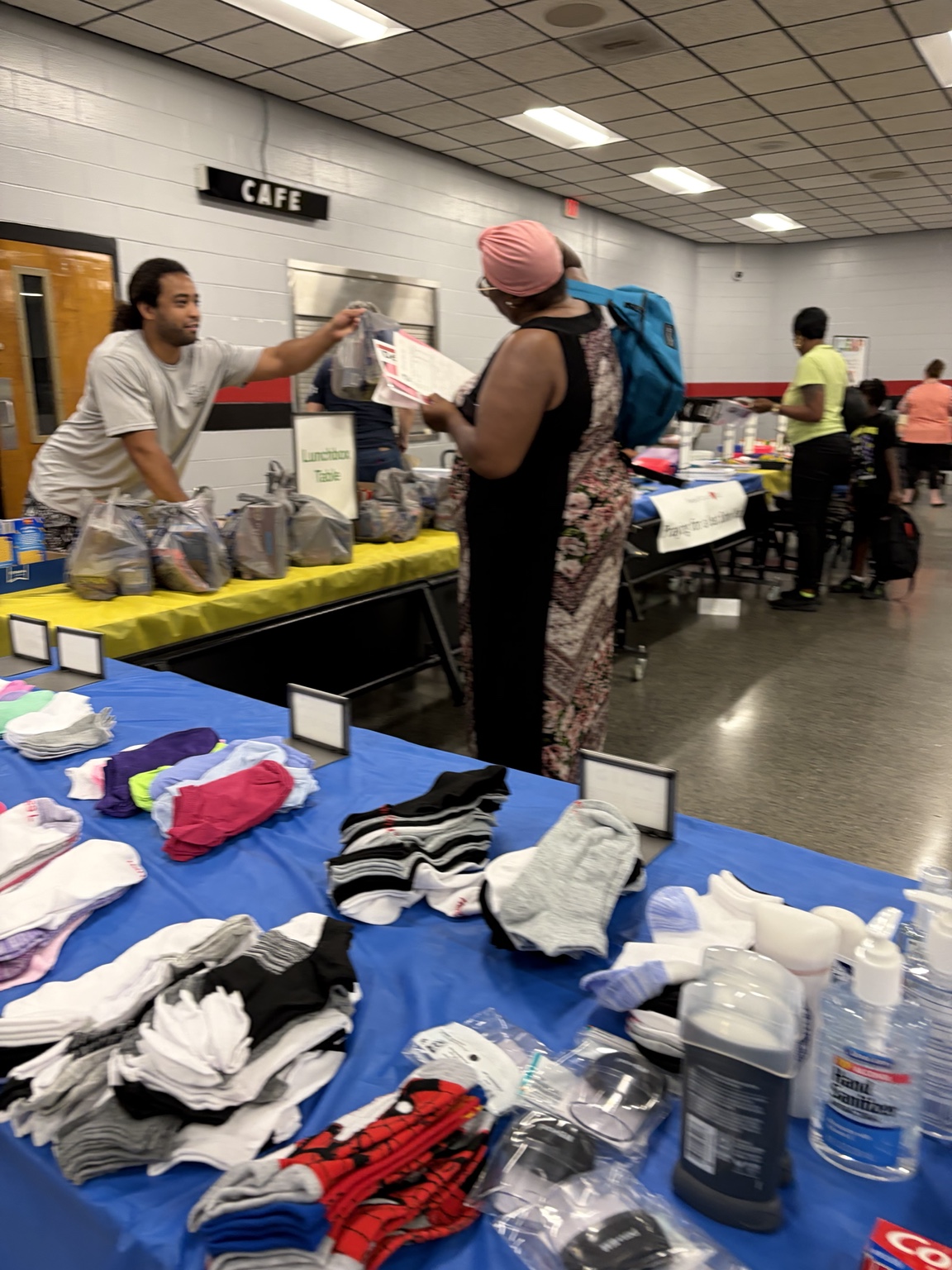 A volunteer handing a lunchbox supply bag to a community member during the school event.