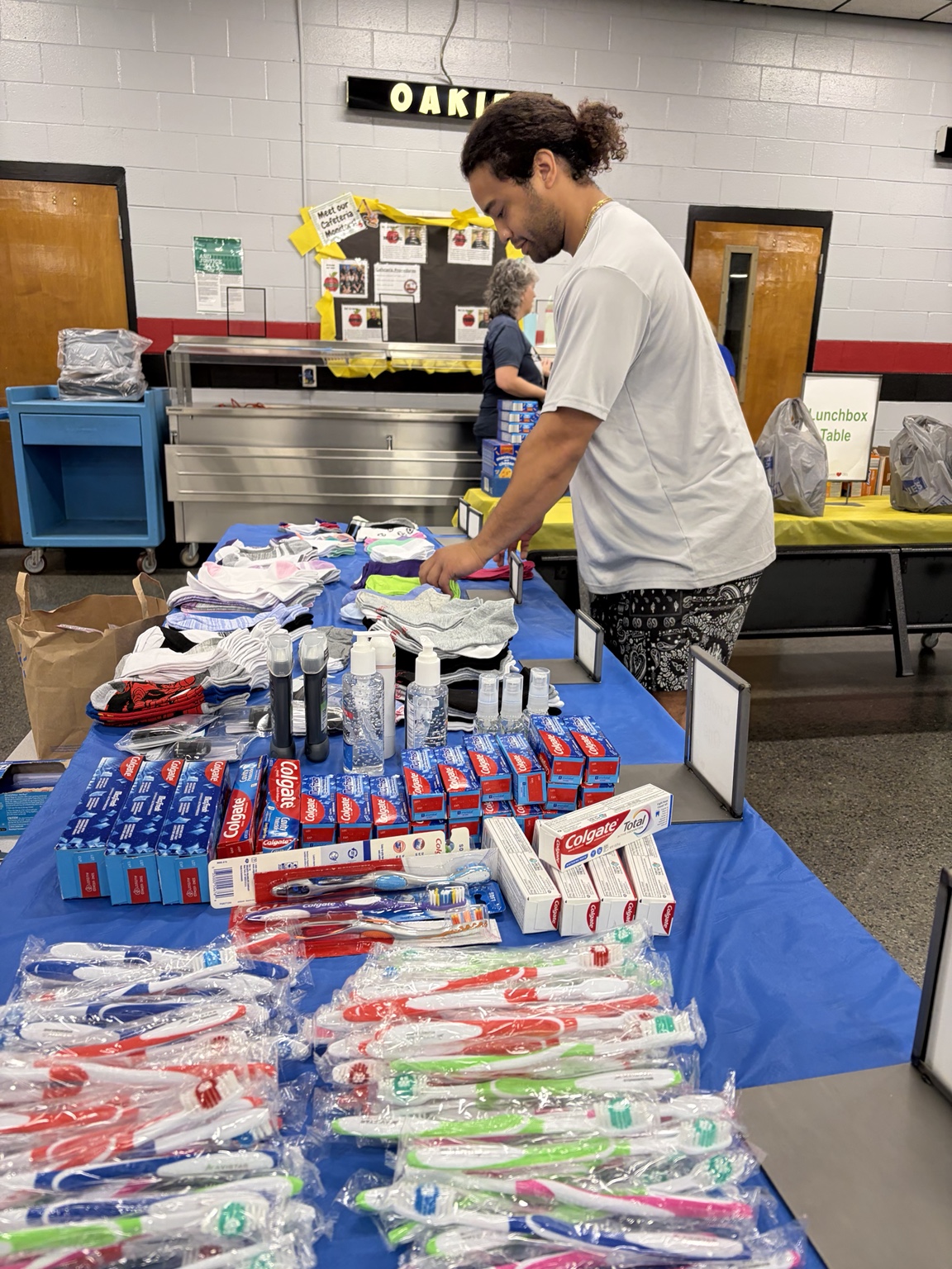 A volunteer organizing toothpaste, toothbrushes, socks, and hygiene supplies on the distribution table.