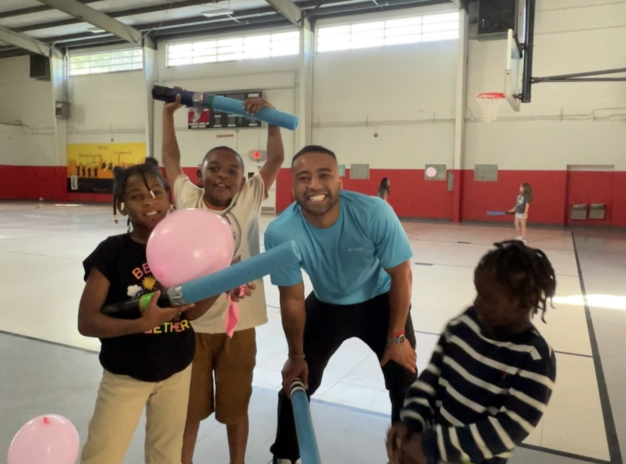 Jimmy Thomas playing with children in a community center gymnasium.