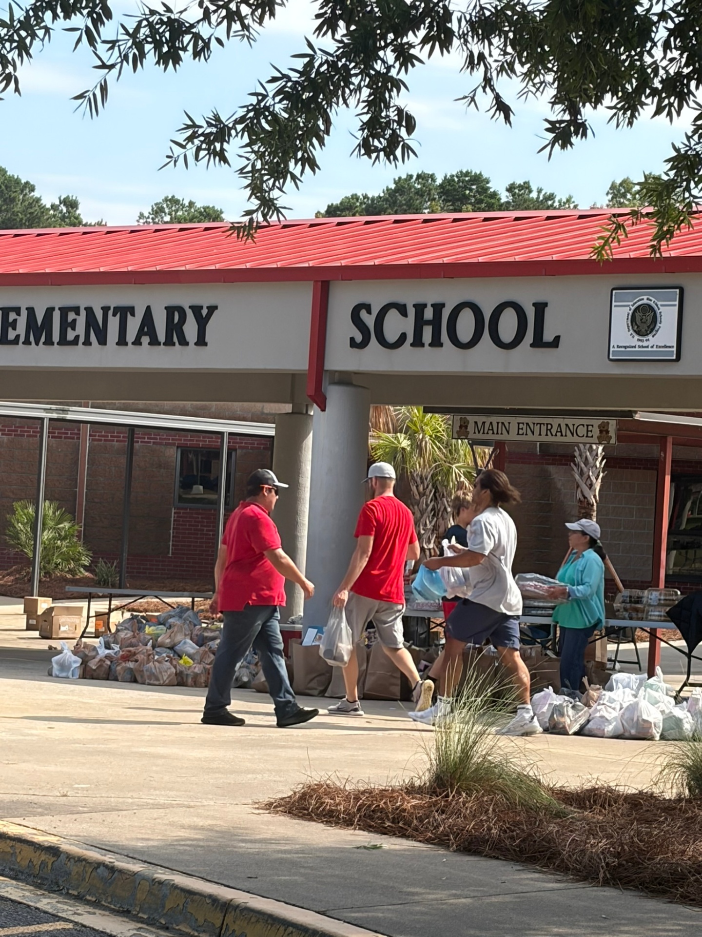 Volunteers preparing food packages near the entrance of a Charleston-area elementary school.