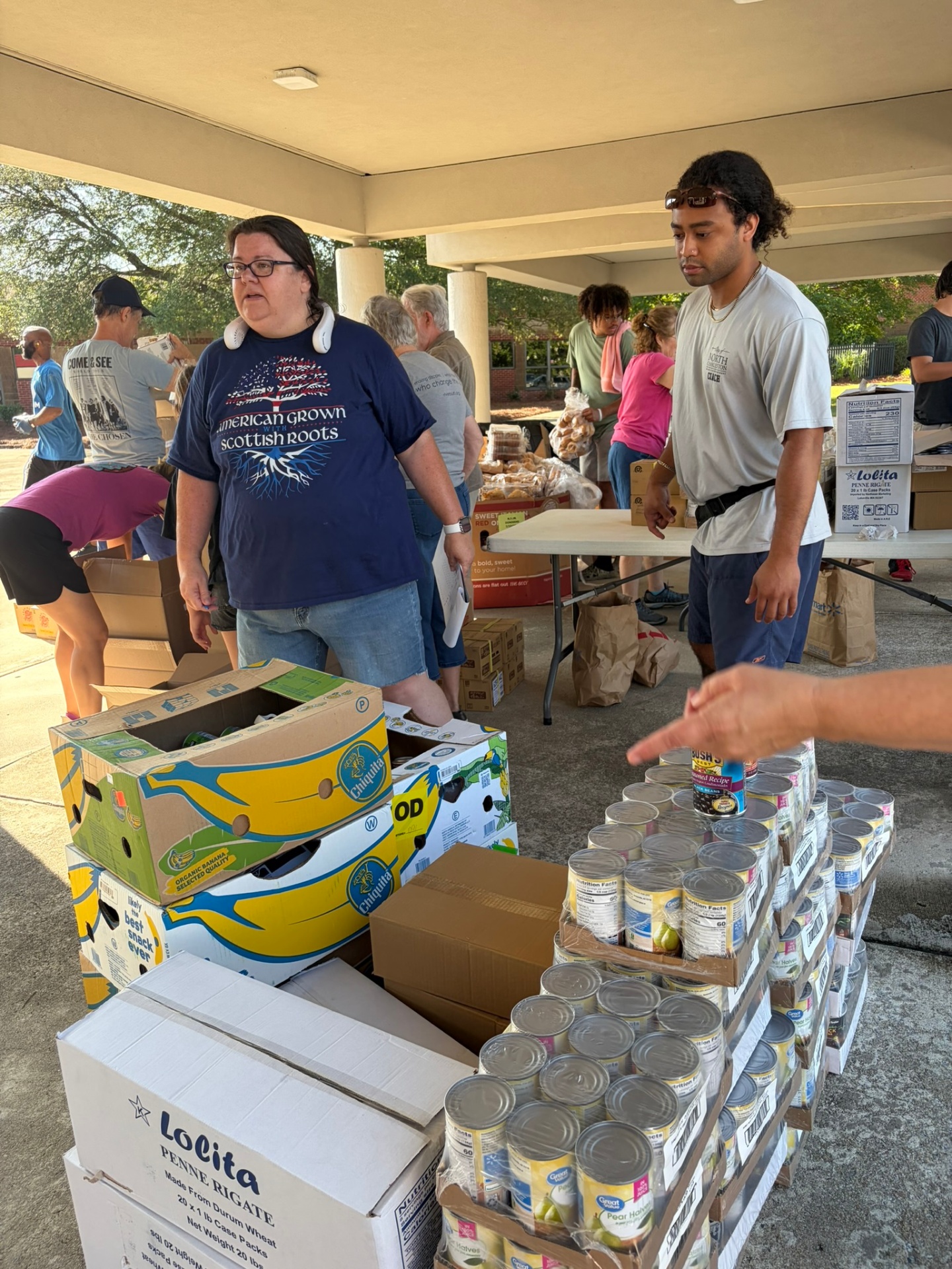 Volunteers standing beside organized boxes and canned food supplies.
