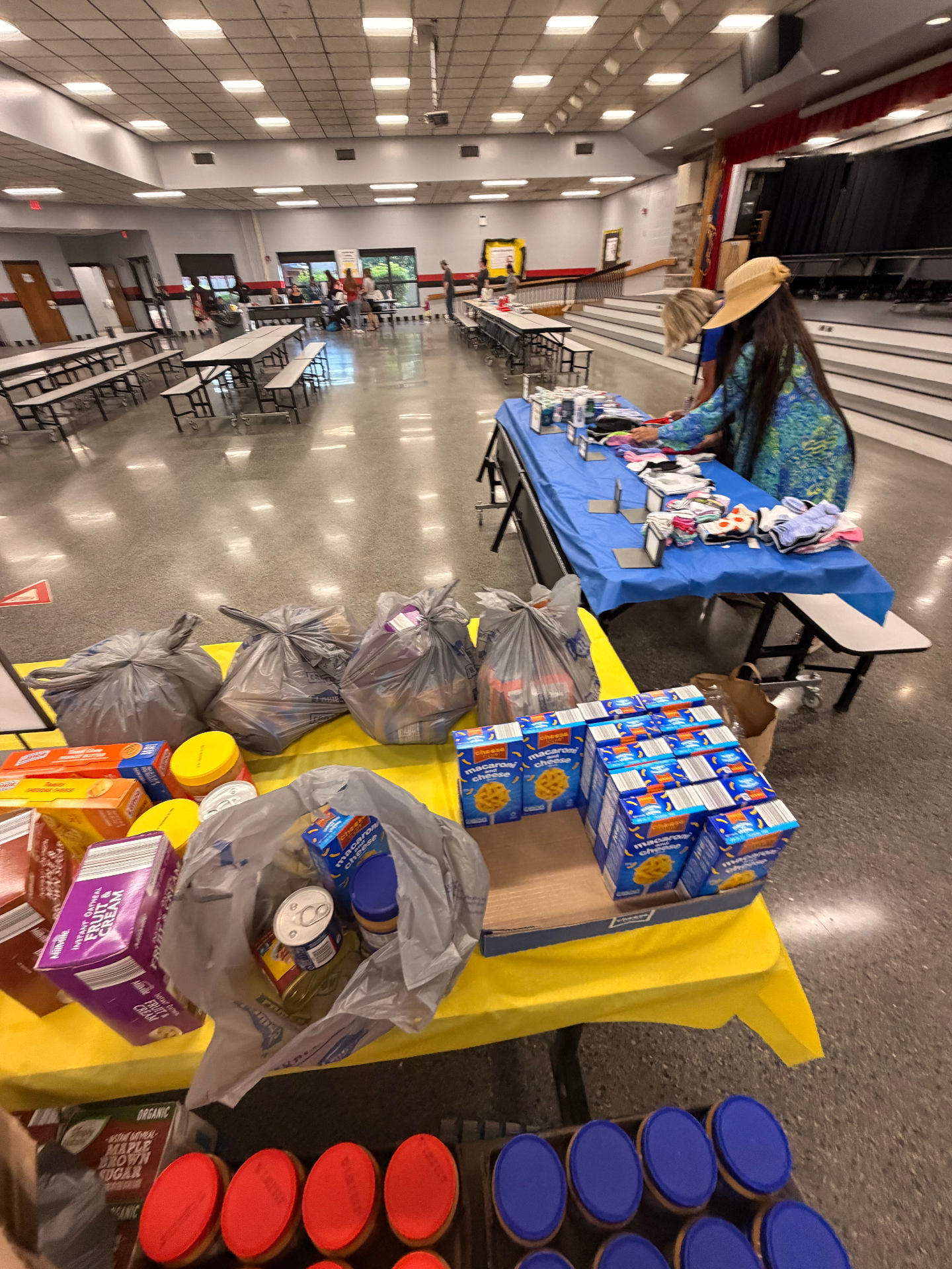 Food, snacks, and household items displayed for family distribution at the school event.